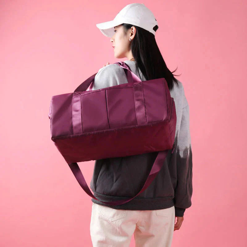Mala desportiva impermeável vermelha com alças e bolso frontal, ideal para viagens e atividades desportivas.